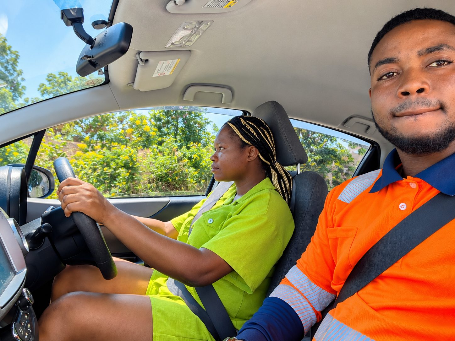 Instructor in orange hi-vis guiding a student at the wheel